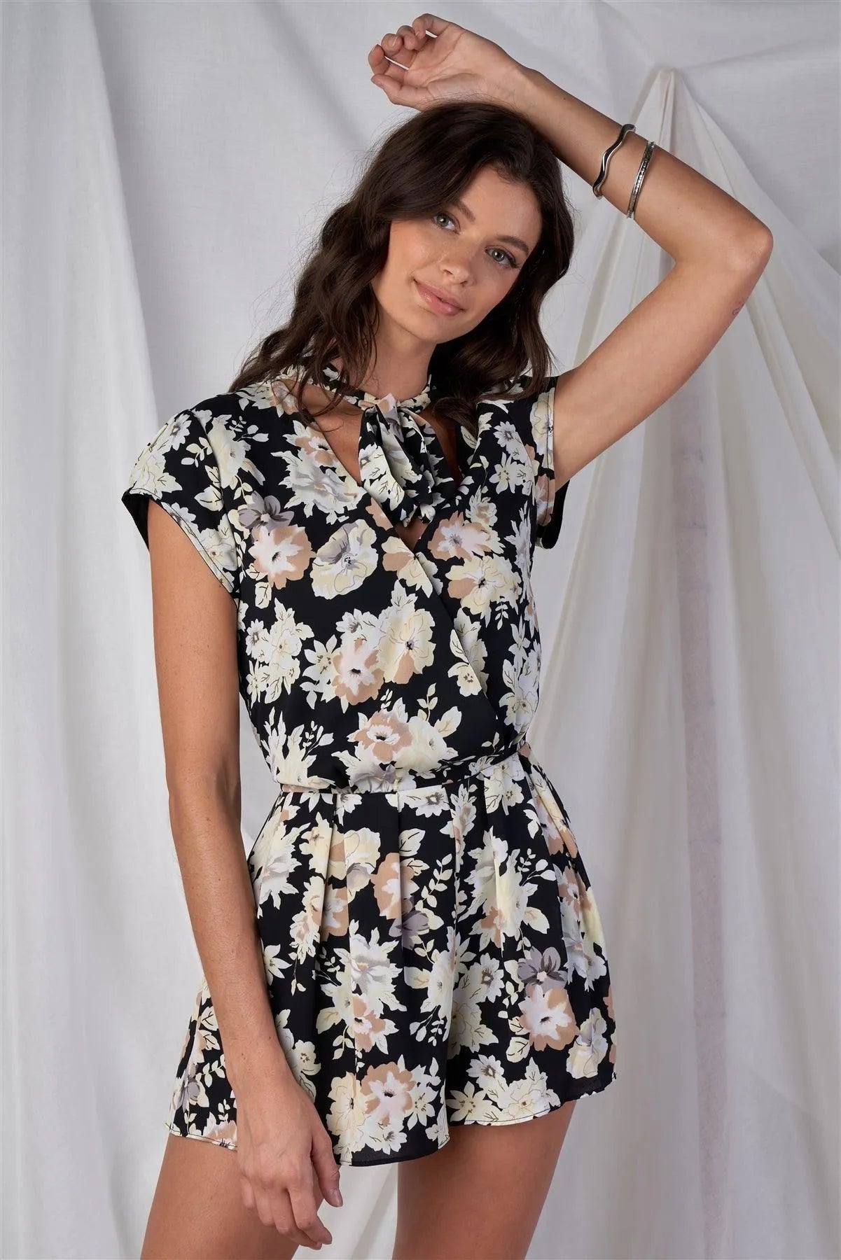 Black Multi Color Floral Print V-Neck Mini Sleeve Tight Fitted Waist Pleated Bottom Romper With Bow Tie Detail - Tasha Apparel Wholesale