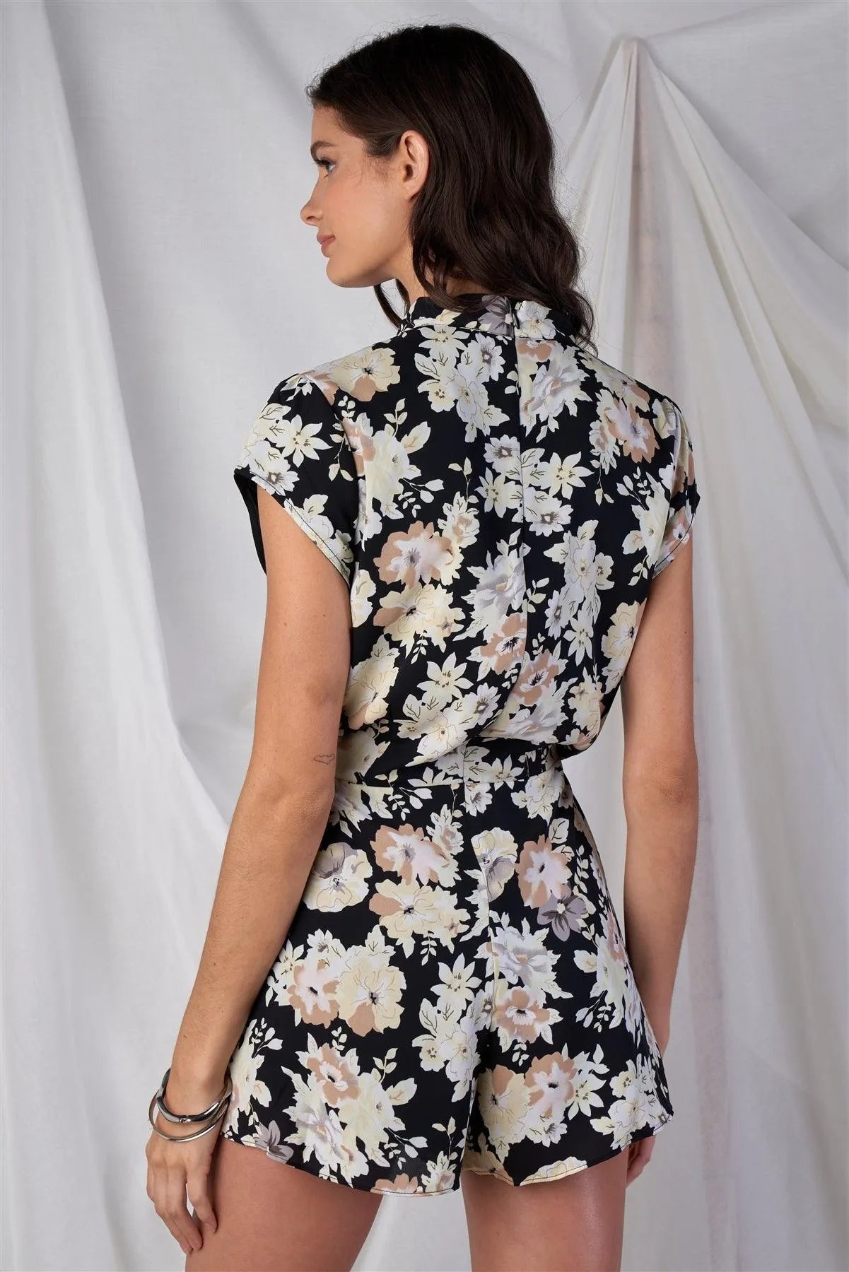 Black Multi Color Floral Print V-Neck Mini Sleeve Tight Fitted Waist Pleated Bottom Romper With Bow Tie Detail - Tasha Apparel Wholesale